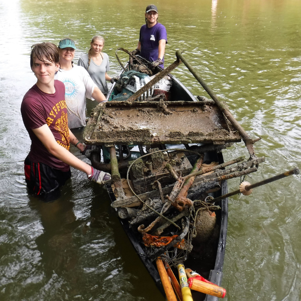 Volunteers alongside a boat in a river.